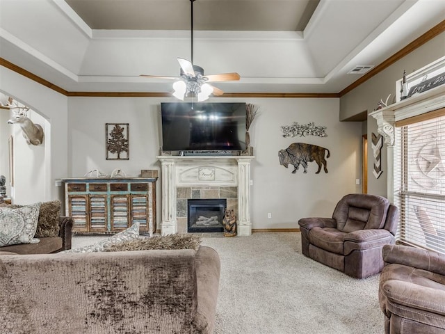 living room with a fireplace, a ceiling fan, a tray ceiling, and carpet floors