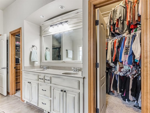 bathroom with a sink, a walk in closet, and double vanity