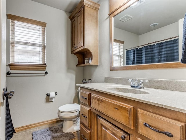 bathroom with vanity, toilet, baseboards, and visible vents