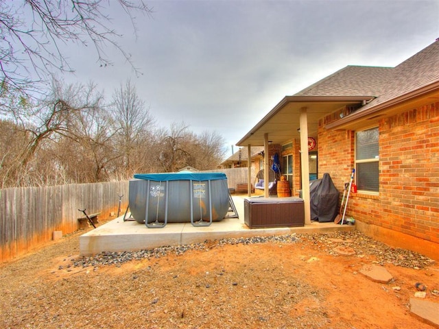 view of yard featuring a patio, a fenced backyard, a fenced in pool, and a hot tub