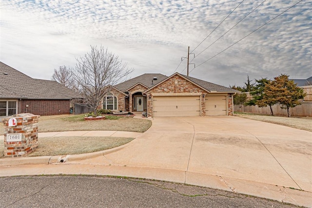 view of front facade featuring fence, brick siding, a garage, and driveway