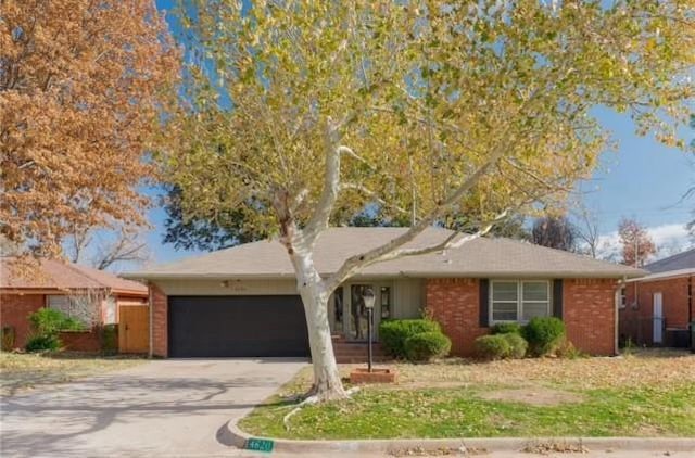 single story home featuring brick siding, driveway, and an attached garage