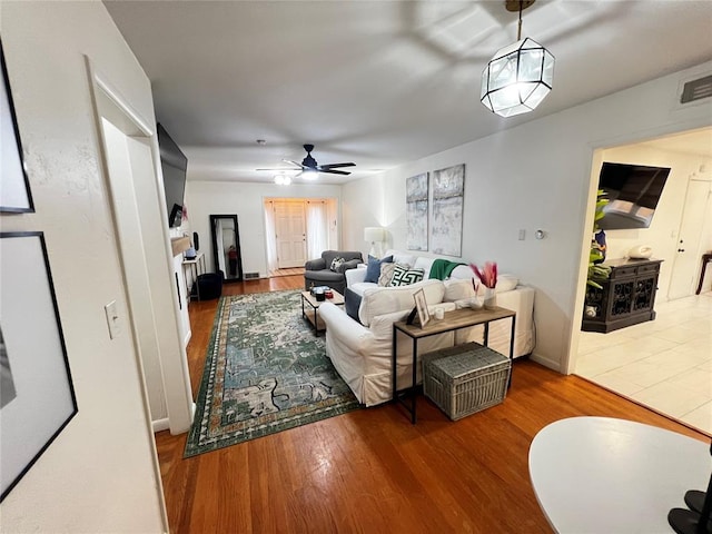 living area with a ceiling fan, wood finished floors, and visible vents