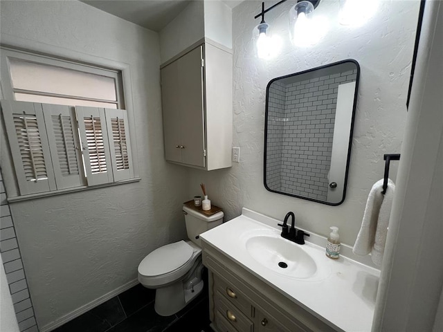 half bathroom with tile patterned floors, toilet, vanity, and a textured wall