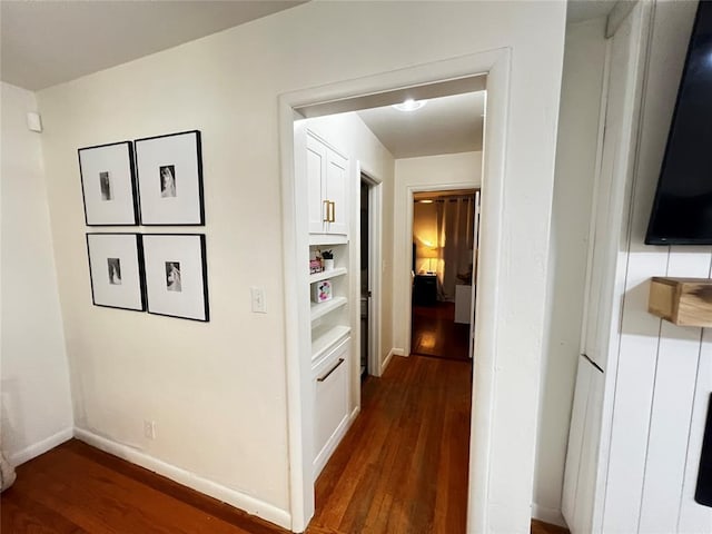 hall with baseboards and wood finished floors