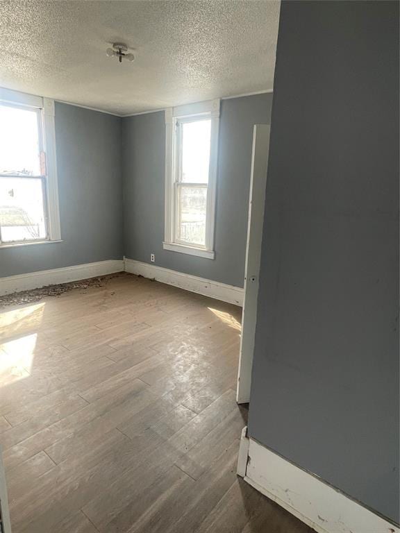 empty room featuring plenty of natural light, wood finished floors, and baseboards