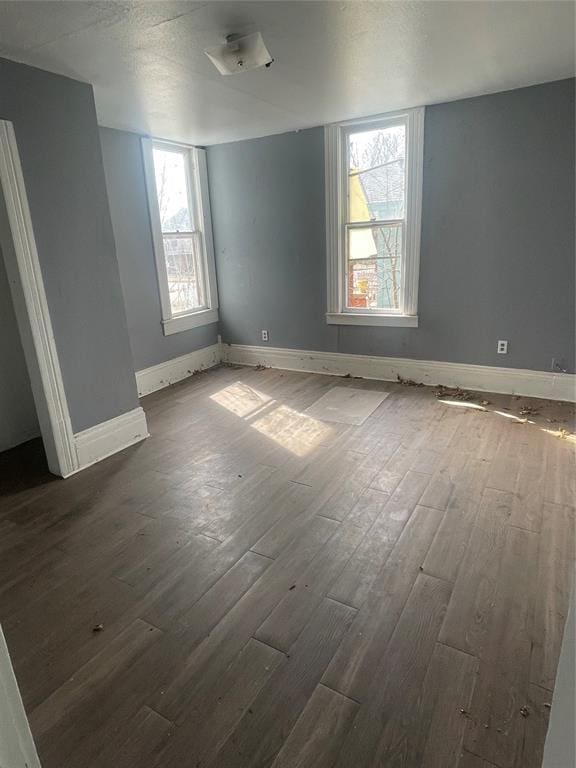 spare room featuring baseboards and dark wood-style flooring