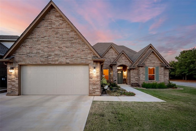 french country home with brick siding, a front lawn, an attached garage, and driveway