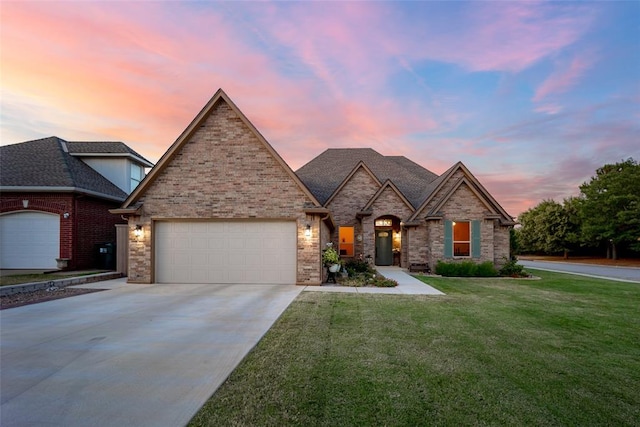 view of front of property featuring a yard, brick siding, a garage, and driveway