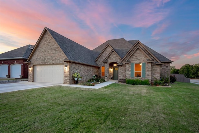 french provincial home featuring a front lawn, concrete driveway, brick siding, and a garage