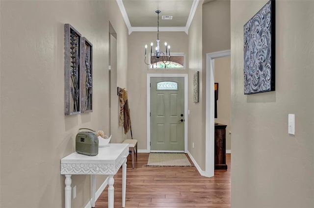 entrance foyer with visible vents, ornamental molding, wood finished floors, baseboards, and a chandelier