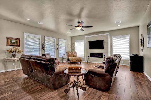 living area with visible vents, a healthy amount of sunlight, baseboards, and hardwood / wood-style flooring