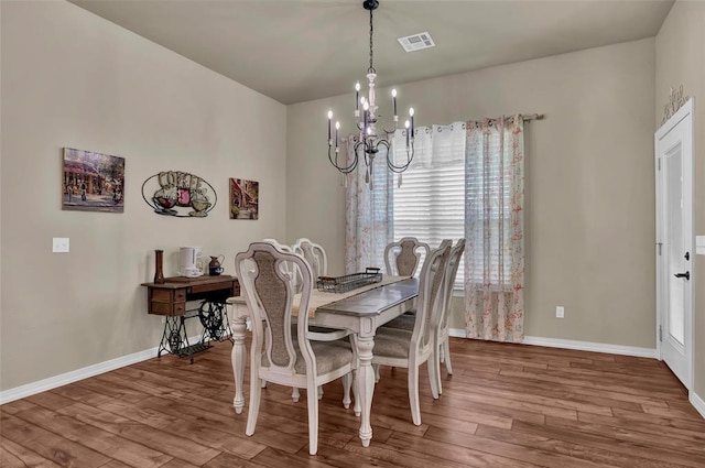 dining room with baseboards, wood finished floors, visible vents, and a chandelier