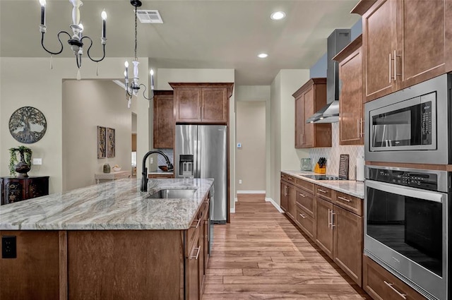 kitchen with light wood finished floors, visible vents, a large island with sink, stainless steel appliances, and a sink