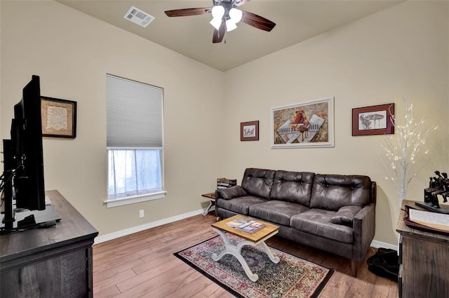 living area featuring a ceiling fan, wood finished floors, visible vents, and baseboards