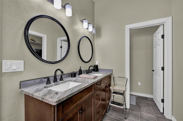 full bath with double vanity, baseboards, and a sink