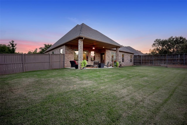 back of property featuring a yard, a patio area, brick siding, and a fenced backyard