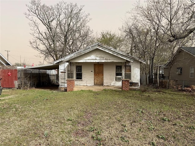 bungalow-style house with a carport, a front lawn, and fence