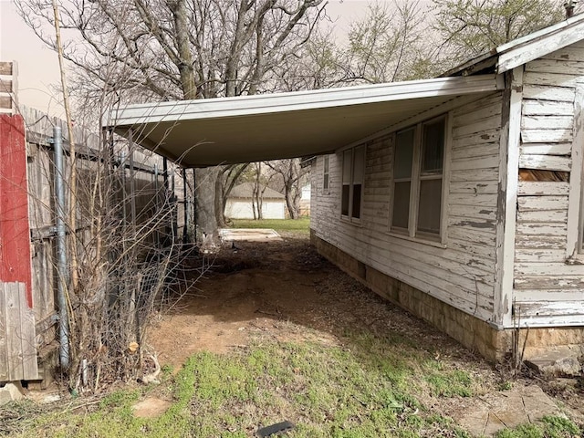 view of parking / parking lot with a carport and fence