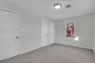 unfurnished bedroom featuring carpet flooring, baseboards, visible vents, and a closet