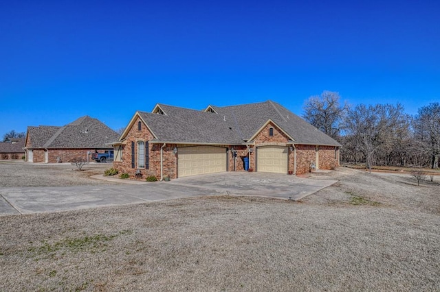 view of front of property featuring brick siding, concrete driveway, a garage, and roof with shingles