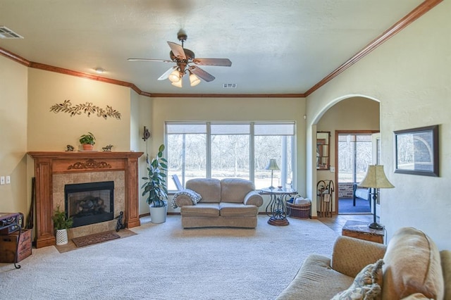 living area featuring visible vents, carpet flooring, ornamental molding, and a ceiling fan