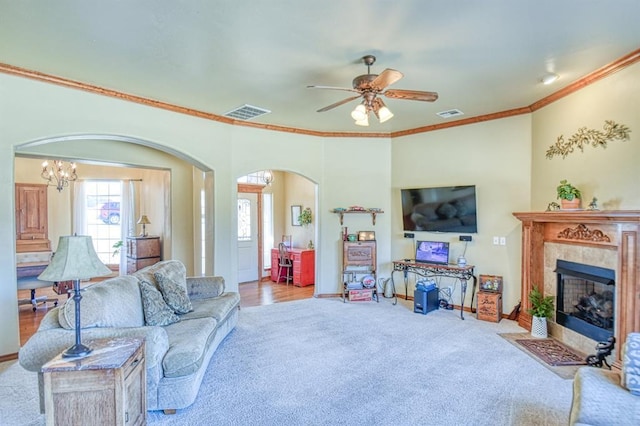 living area featuring arched walkways, visible vents, ceiling fan with notable chandelier, and carpet