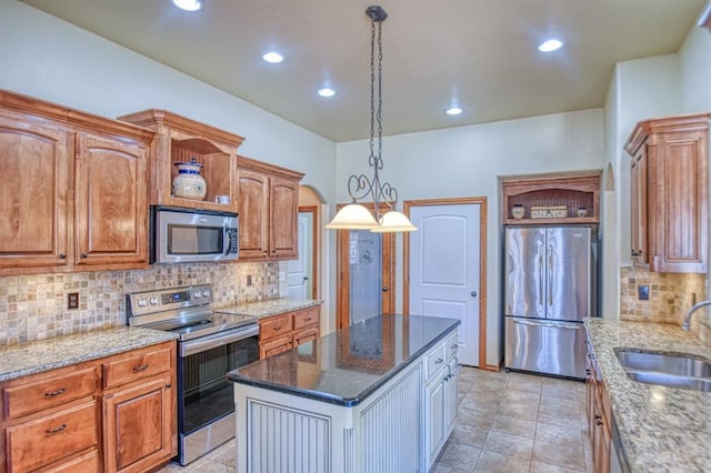 kitchen with a sink, light stone countertops, appliances with stainless steel finishes, and a center island