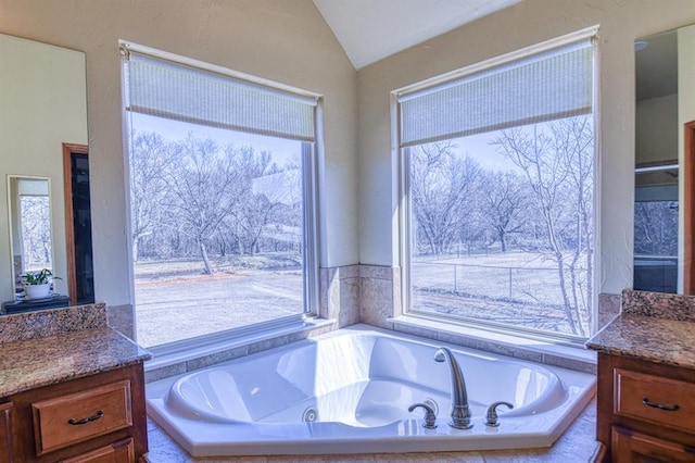 bathroom with vanity, vaulted ceiling, and a garden tub