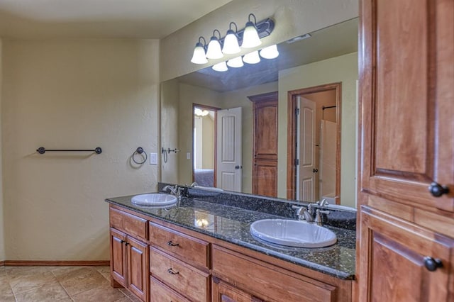 full bathroom with double vanity, tile patterned floors, baseboards, and a sink