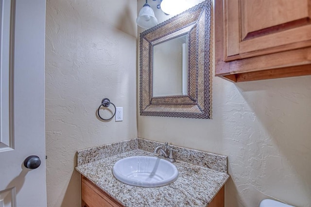 half bath with vanity and a textured wall