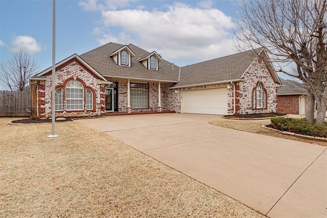 view of front facade featuring fence, roof with shingles, concrete driveway, a garage, and brick siding