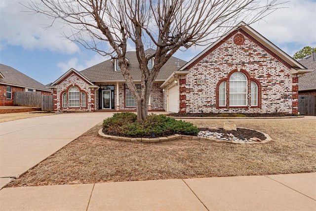 view of front of home with fence, concrete driveway, a shingled roof, a garage, and brick siding