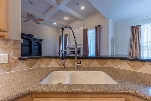 kitchen with crown molding, beam ceiling, a fireplace, coffered ceiling, and a sink