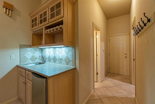 kitchen featuring a sink, glass insert cabinets, light tile patterned flooring, light countertops, and decorative backsplash