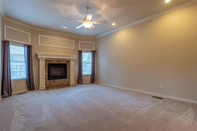 unfurnished living room with ornamental molding, a ceiling fan, carpet floors, a premium fireplace, and baseboards