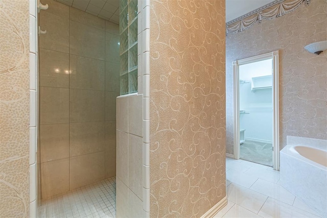 bathroom featuring wallpapered walls, a garden tub, tile patterned flooring, and tiled shower