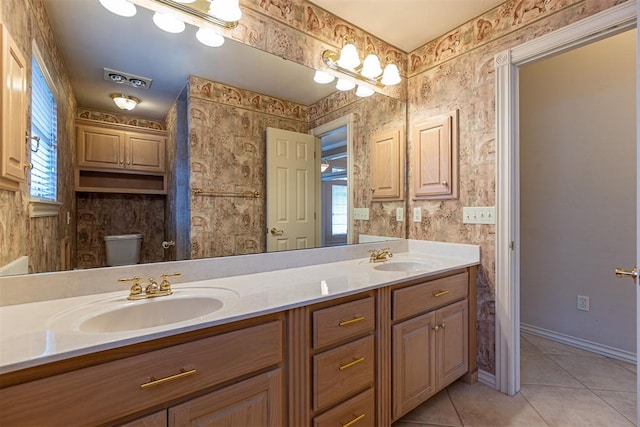 bathroom with a sink, double vanity, tile patterned floors, and wallpapered walls