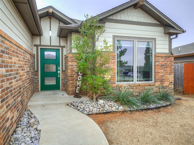 doorway to property featuring brick siding and fence