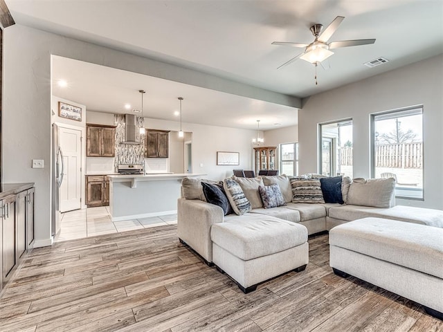 living area with recessed lighting, visible vents, light wood finished floors, and ceiling fan with notable chandelier