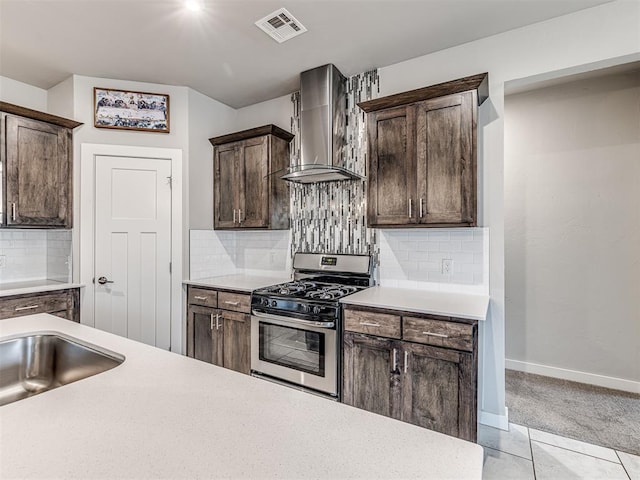 kitchen with visible vents, dark brown cabinets, wall chimney range hood, light countertops, and stainless steel gas stove