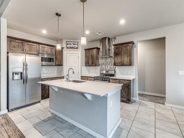 kitchen featuring wall chimney range hood, dark brown cabinetry, light countertops, appliances with stainless steel finishes, and a sink