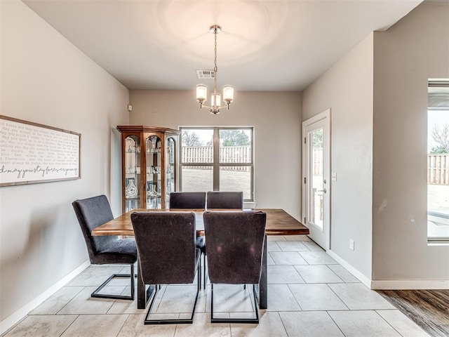 dining space featuring light tile patterned floors, visible vents, baseboards, and a chandelier