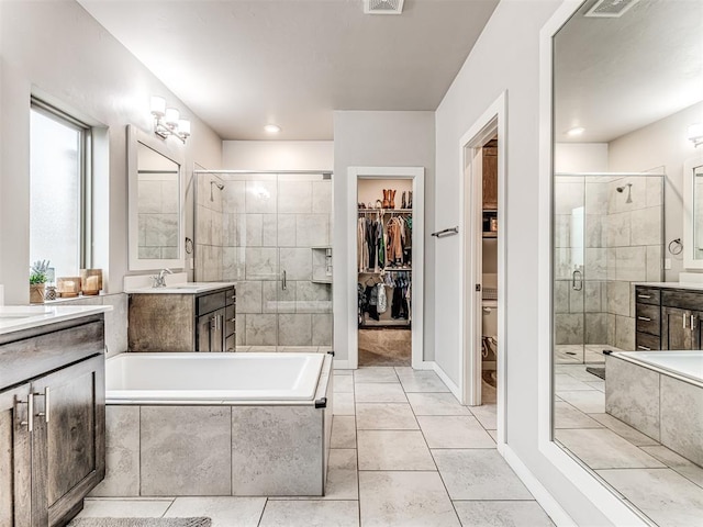 full bathroom with a walk in closet, visible vents, a stall shower, tiled bath, and vanity