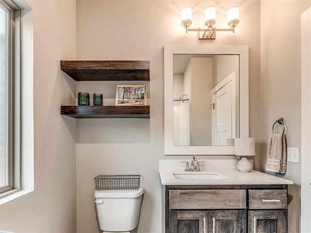 bathroom with vanity, toilet, and a healthy amount of sunlight