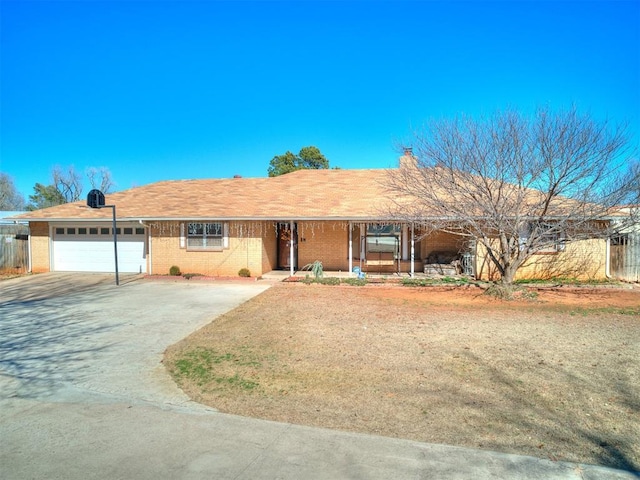 ranch-style house with brick siding, covered porch, driveway, and a garage