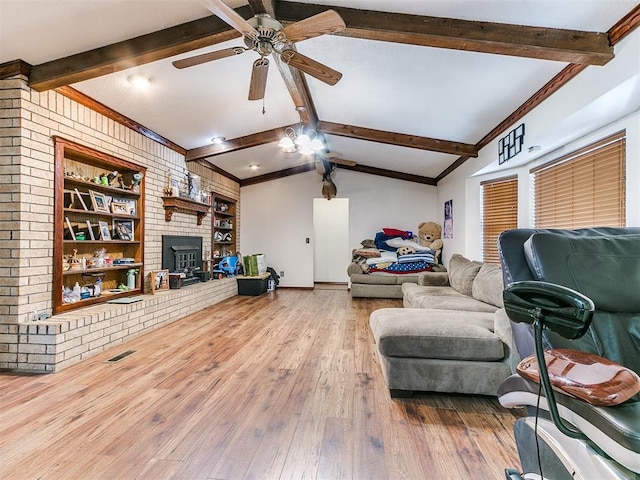 living room with brick wall, vaulted ceiling with beams, ceiling fan, a fireplace, and wood-type flooring