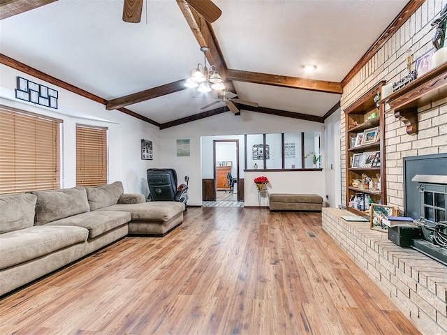 living area with vaulted ceiling with beams, baseboards, ceiling fan, a fireplace, and wood-type flooring