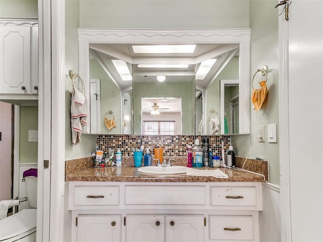 bathroom featuring tasteful backsplash, ceiling fan, vanity, and toilet