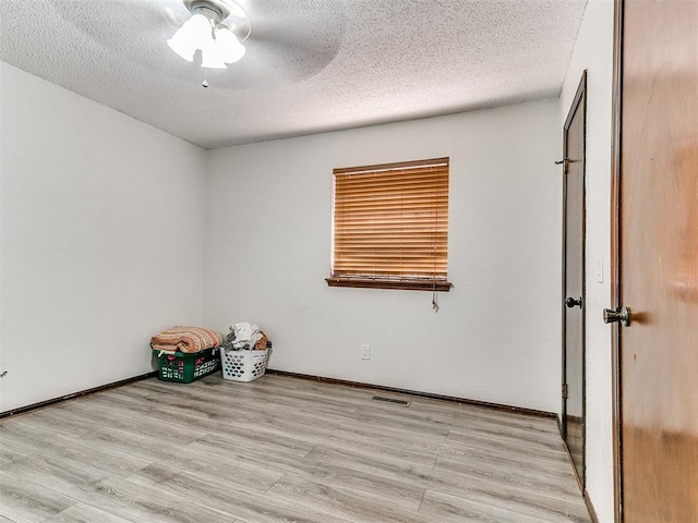 unfurnished room featuring baseboards, a textured ceiling, and light wood-style flooring